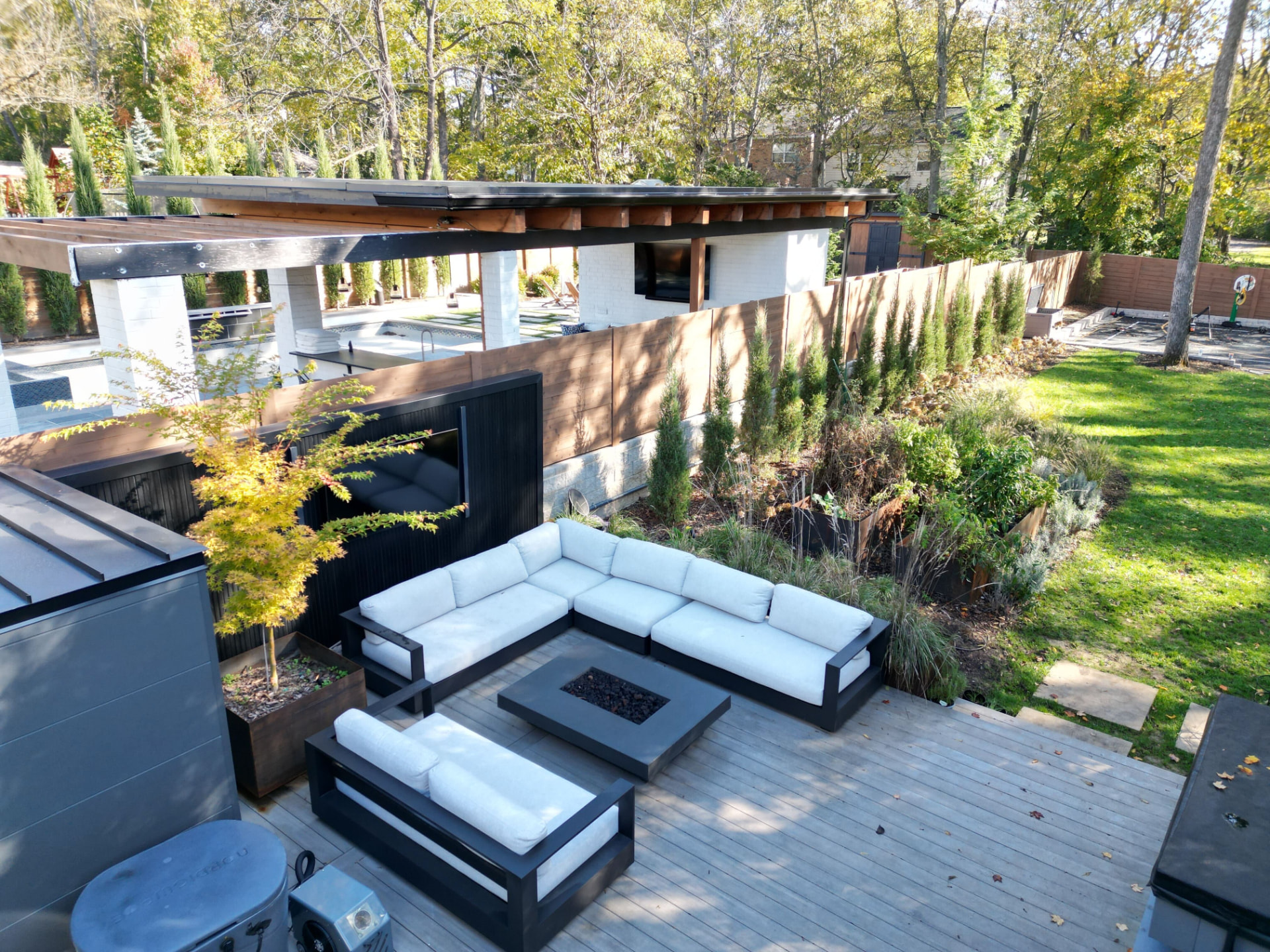 Deck lounge with sectional seating around a fire table and steel planters
