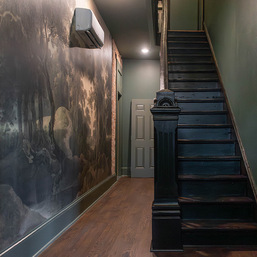Restored hallway with black staircase, mural wall and refinished wood floors