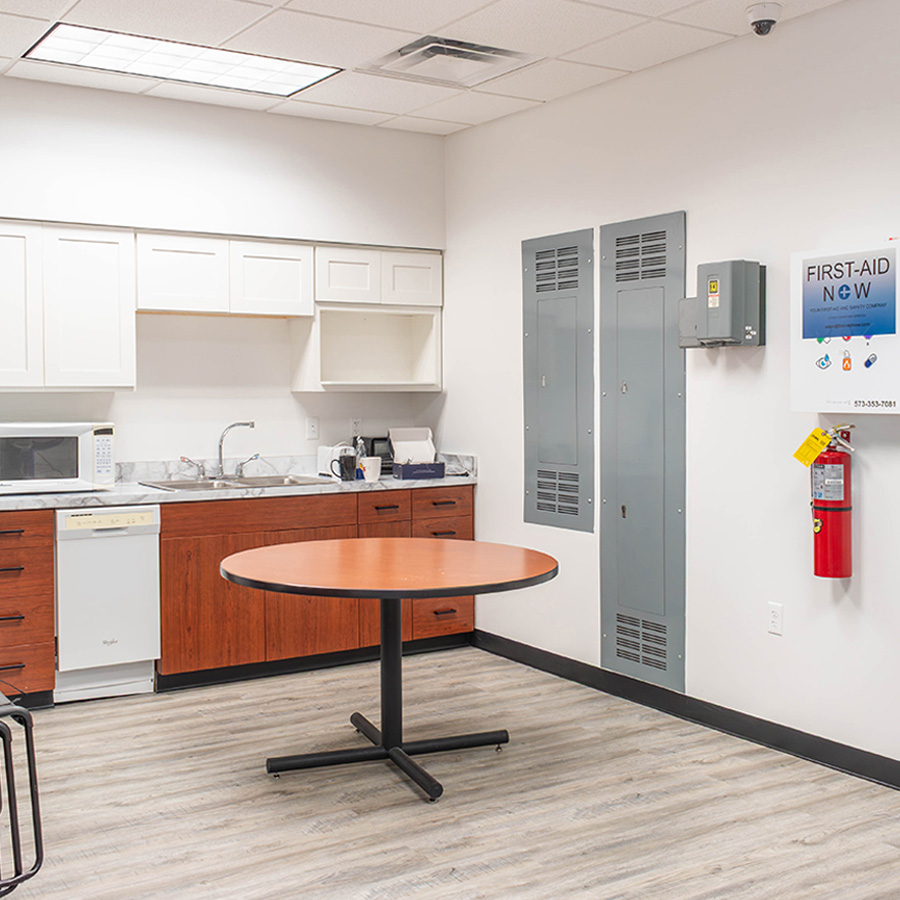 Updated break room with white upper cabinets, stone-look counters and light plank flooring