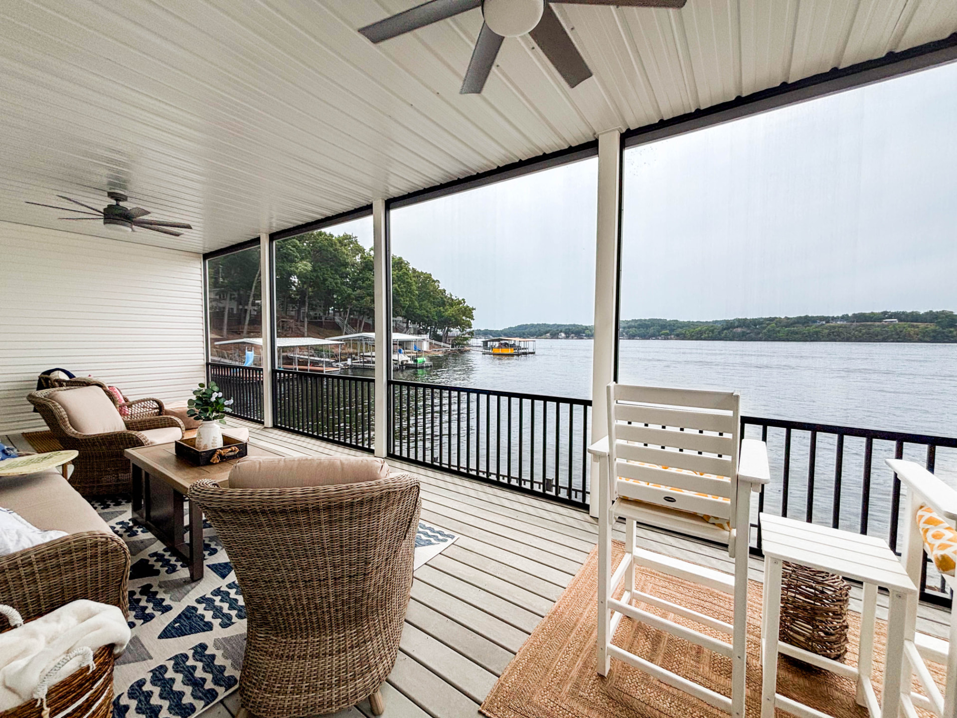 Screened lakeside porch with ceiling fans, wicker seating and a view of the water