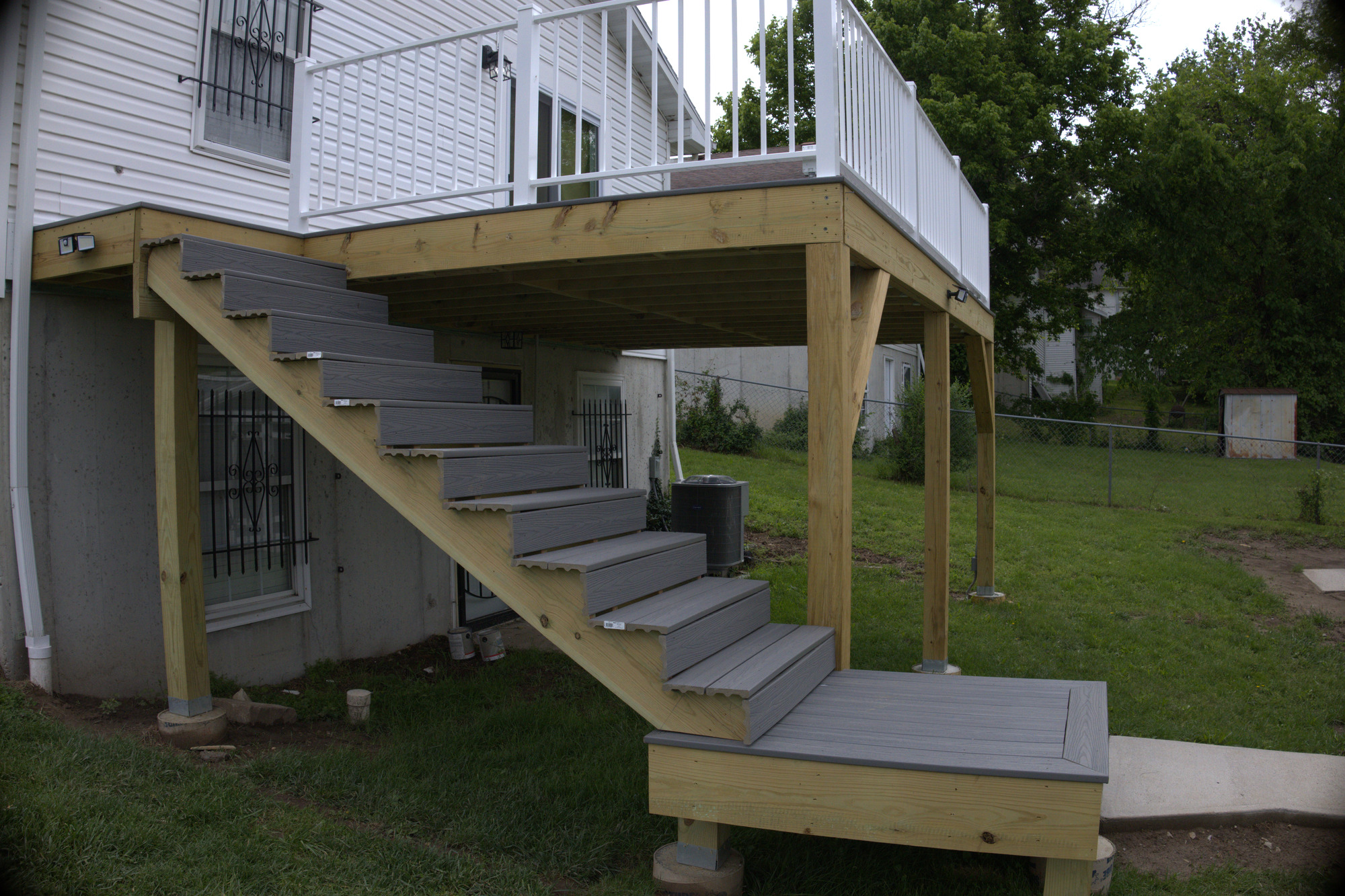 Raised backyard deck with new framing, composite decking and a wide stair run to the yard