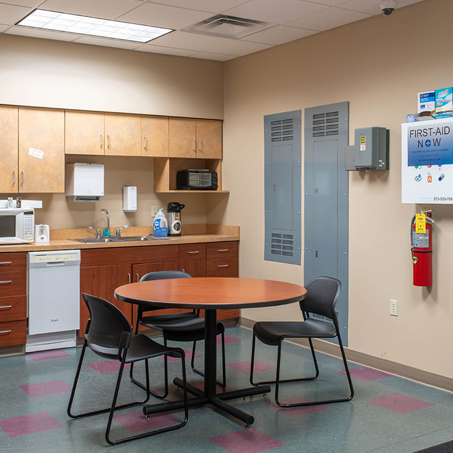 Dated break room with tan walls, laminate cabinets and worn tile flooring