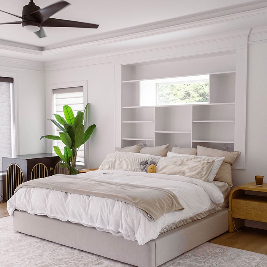 Finished bedroom with white walls, built-in shelving, upholstered bed and wood flooring