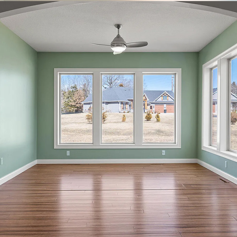 Empty room with green walls, dark wood flooring and a ceiling fan
