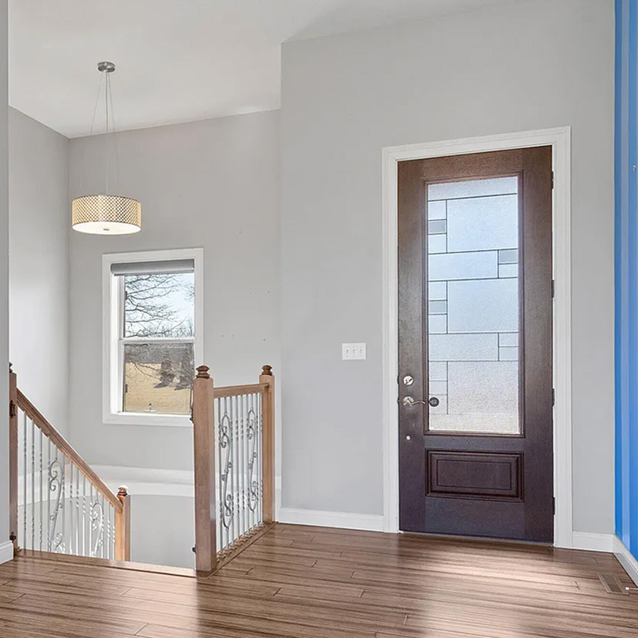 Entry landing with wood railing, scrolled iron balusters and a drum pendant light