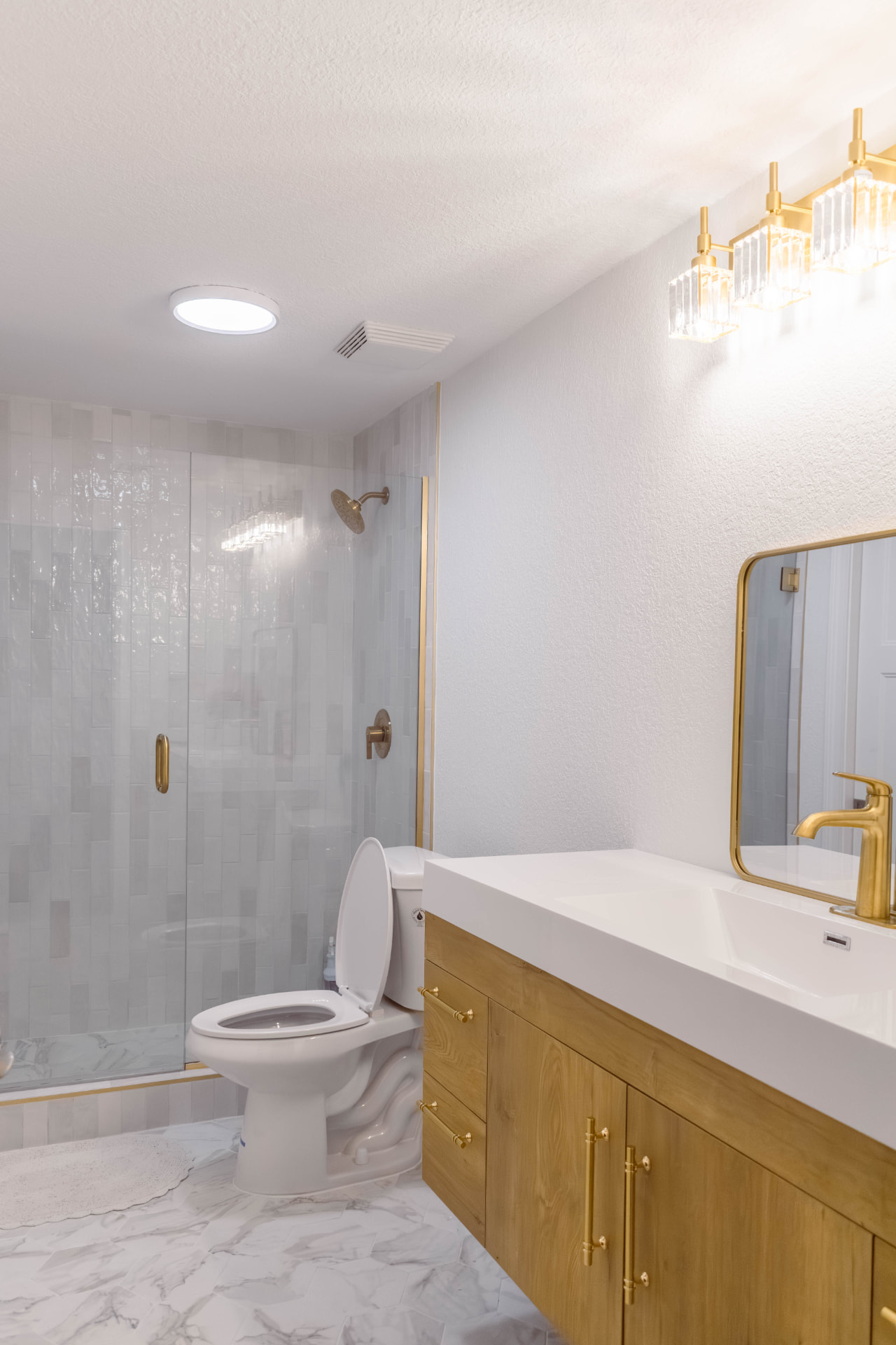 Tiled walk-in shower with a glass enclosure and brass fixtures