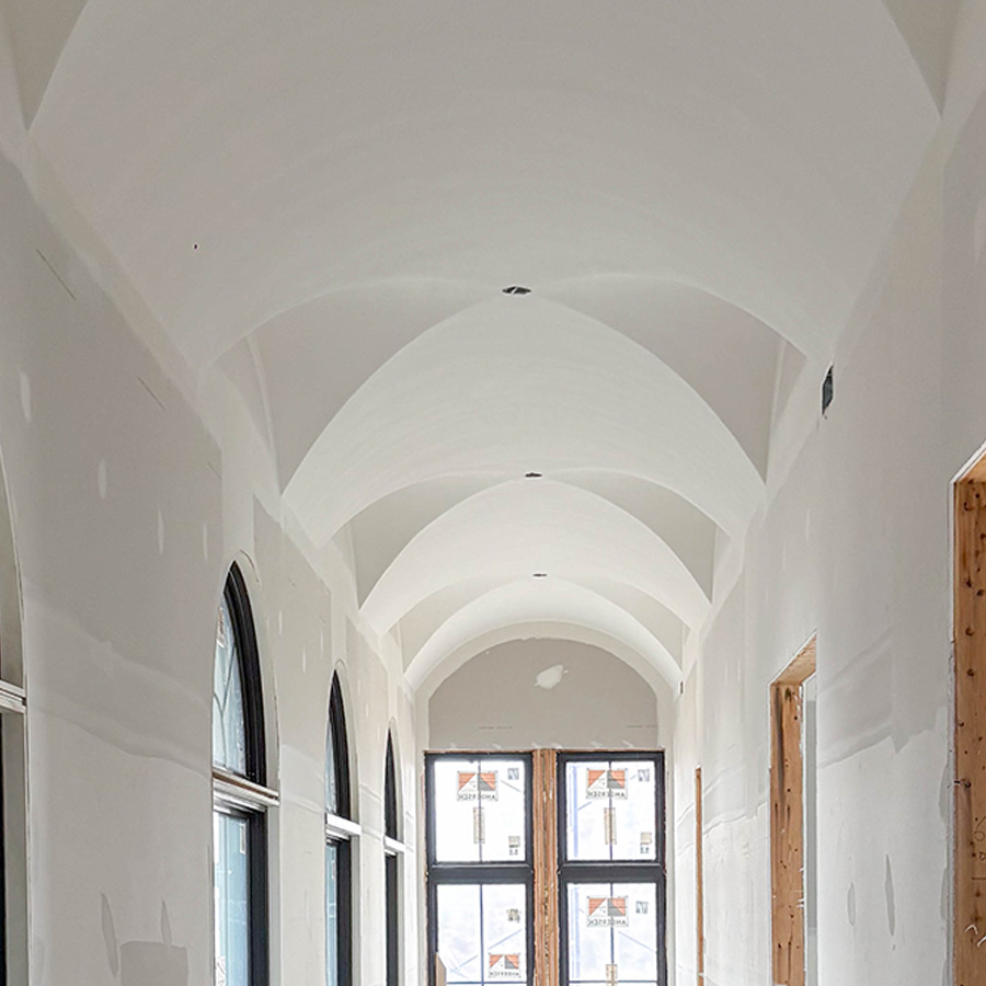 Finished hallway with white groin-vaulted ceiling and tall arched windows