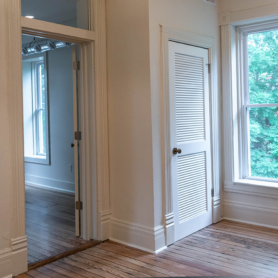Bright bedroom with fresh white trim, louvered closet door and refinished floors
