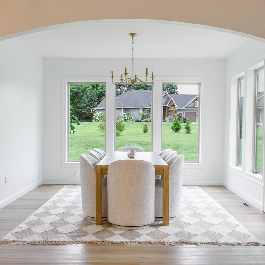 Bright dining room with white walls, light wood floors and a brass chandelier