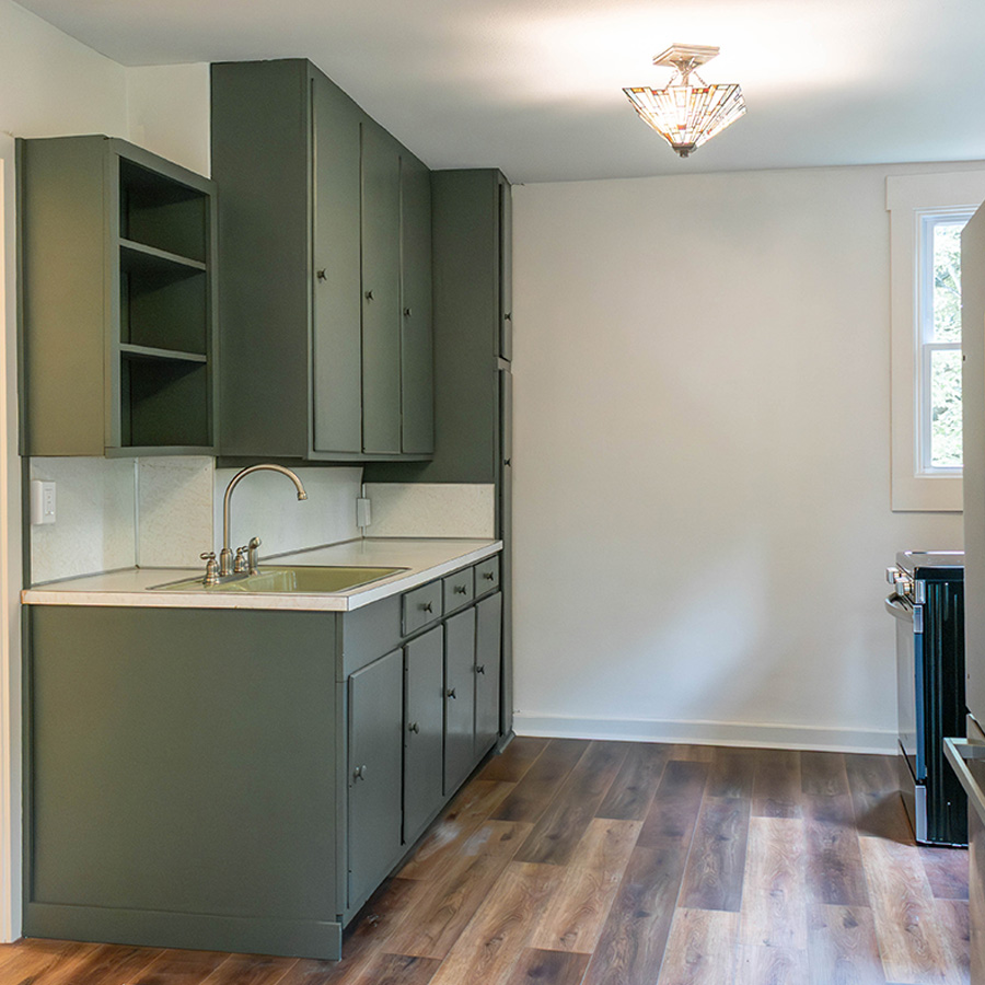 Refreshed kitchen with green cabinetry, new counters, sink and plank flooring
