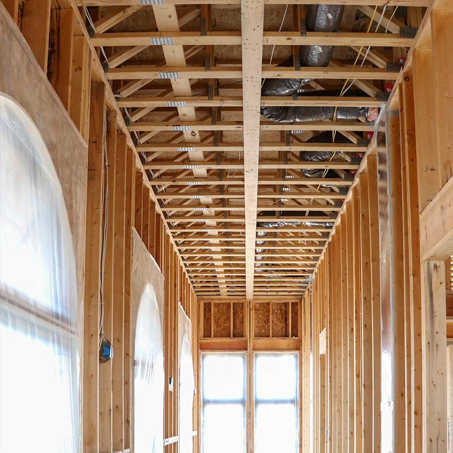 Hallway under construction with exposed wood framing, ductwork and rough openings