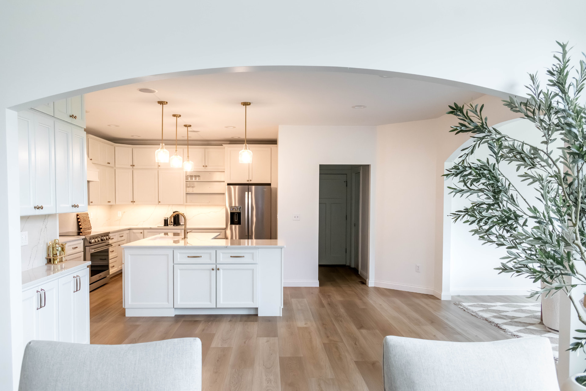 Open remodeled kitchen with white cabinetry, quartz island and pendant lighting