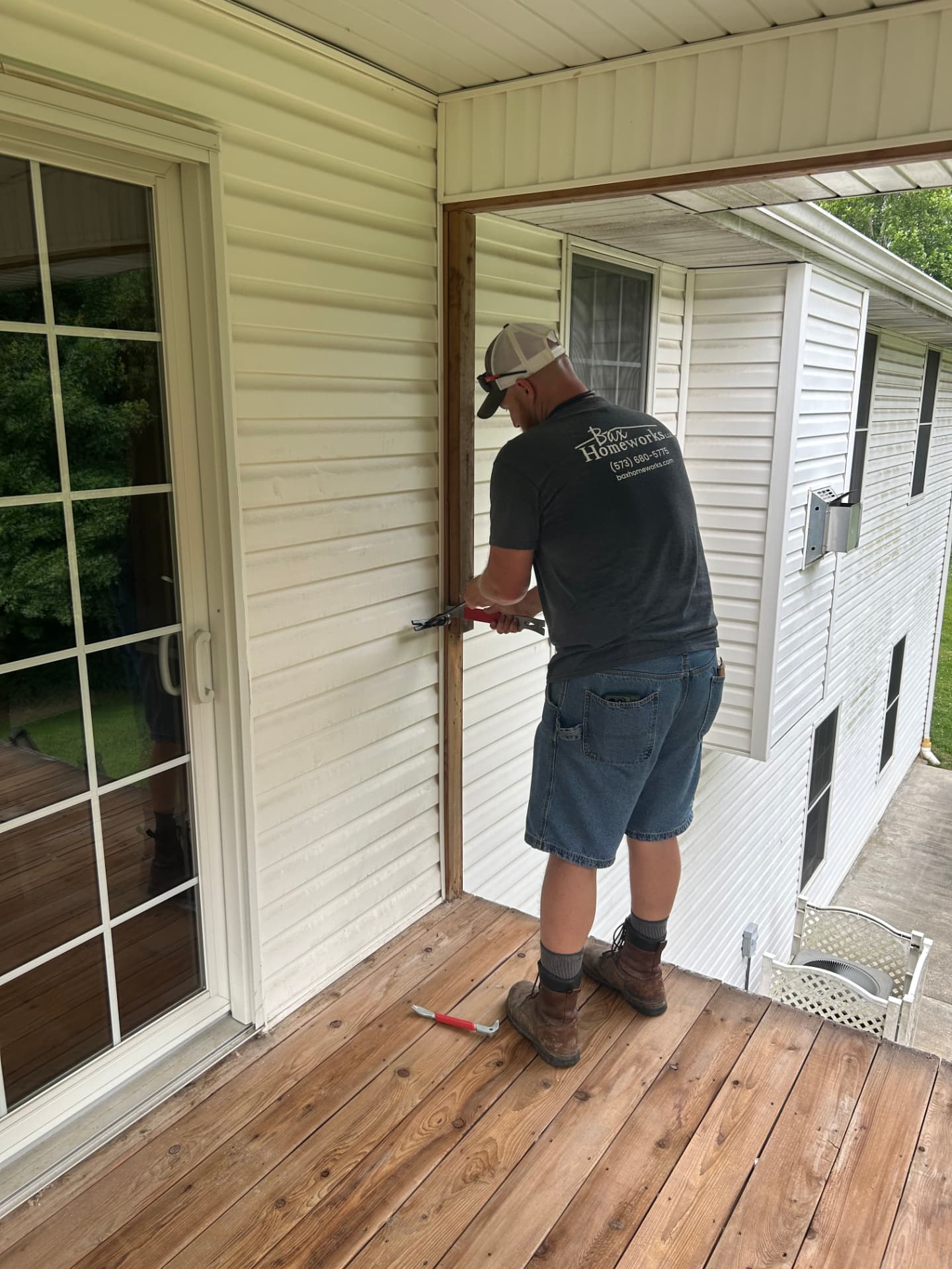 Bax Homeworks technician repairing exterior siding beside a deck door