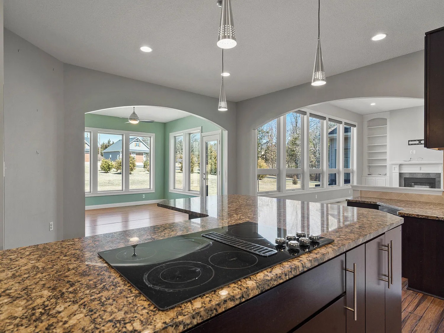 Kitchen island with speckled granite counters, dark cabinets and a black cooktop